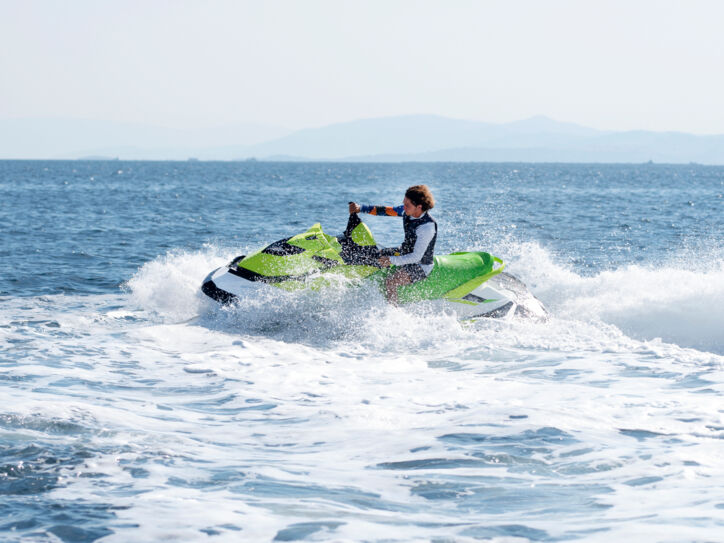 Eine Person fährt mit grünem Jetski auf dem offenen Meer