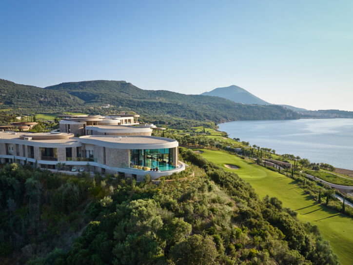 Hotelanlage inmitten einer grünen Hügellandschaft am Meer.