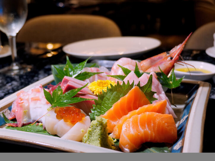 Verschiedene Sashimi Sushi und Scampi auf einem dekorierten Teller in einem Restaurant.