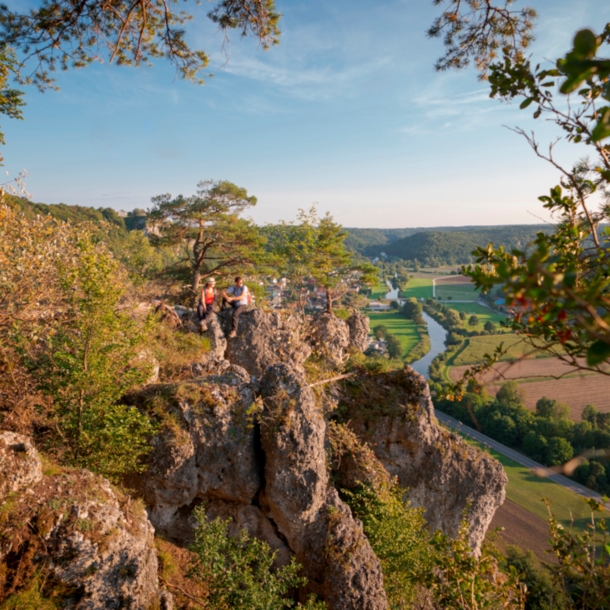 Zwei Wanderer sitzen auf einem Felsen hoch über der Altmühl