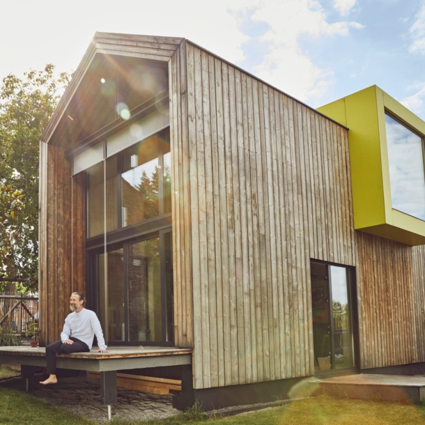 Ein Mann sitzt auf der Terrasse eines Tiny Houses