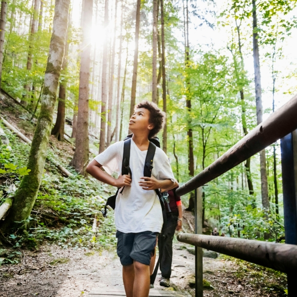 Ein Junge mit Rucksack wandert durch den Wald und beobachtet die Natur