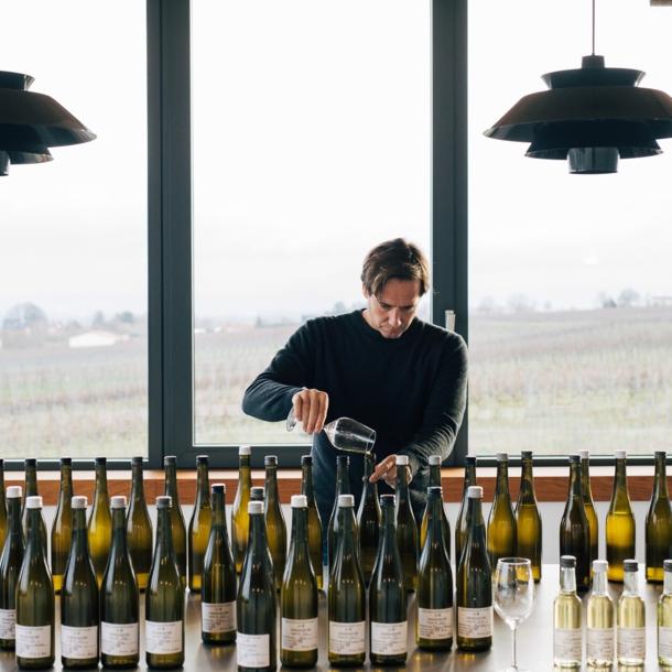 Winzer Jochen Dreissigacker beim Wein einschenken vor einem Tisch mit Weinflaschen