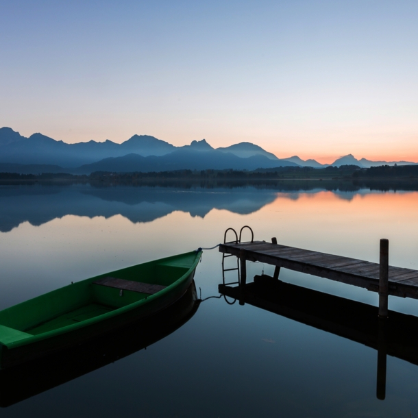 Der See Hopfen in den Bayerischen Alpen mit Boot und Steg bei Dämmerung