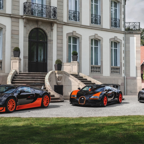 Drei Modelle von Bugatti vor einem Schloss