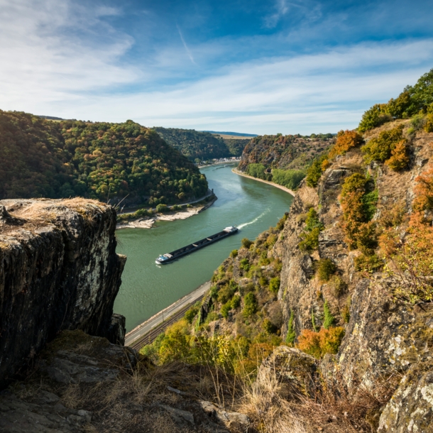 Panoramablick auf Rheinkurve mit Containerschiff von einem Plateau in felsiger Umgebung