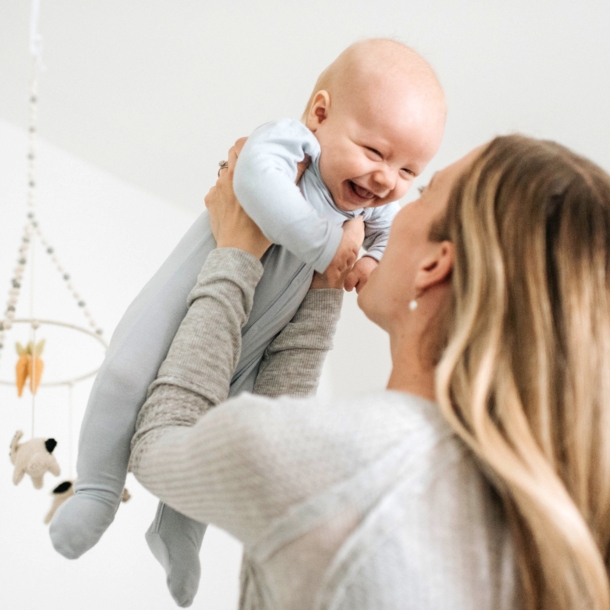 Frau hebt lachendes Baby in die Luft