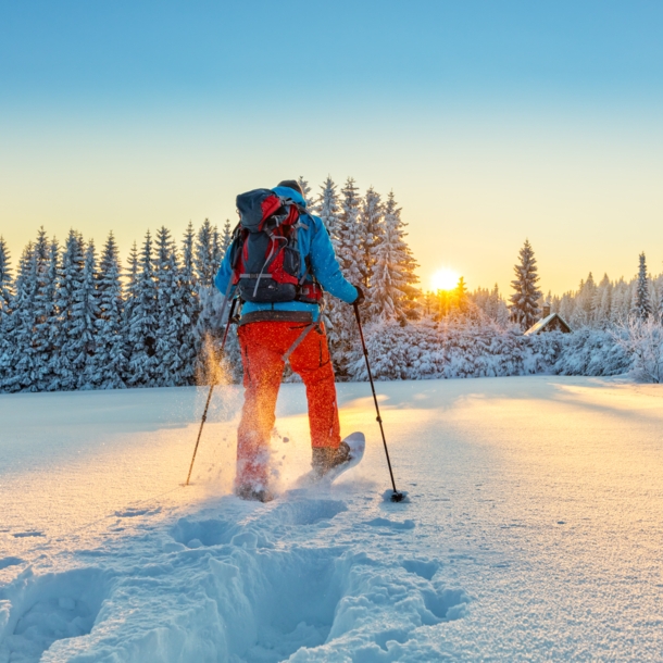 Mann von hinten beim Wandern durch eine Winterlandschaft