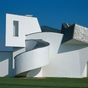 Ein weißes, architektonisch verspieltes Gebäude auf einer grünen Wiese.