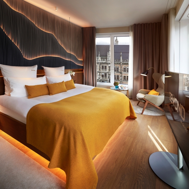 Modernes, stilvolles Hotelzimmer mit großem Doppelbett und Blick auf den Münchener Marienplatz