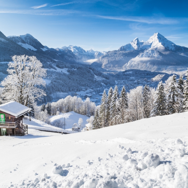 Eine schneebedeckte Berglandschaft, im Vordergrund steht eine kleine Holzhütte