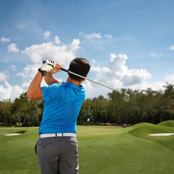 Ein Mann von hinten beim Abschlag auf einem Golfplatz