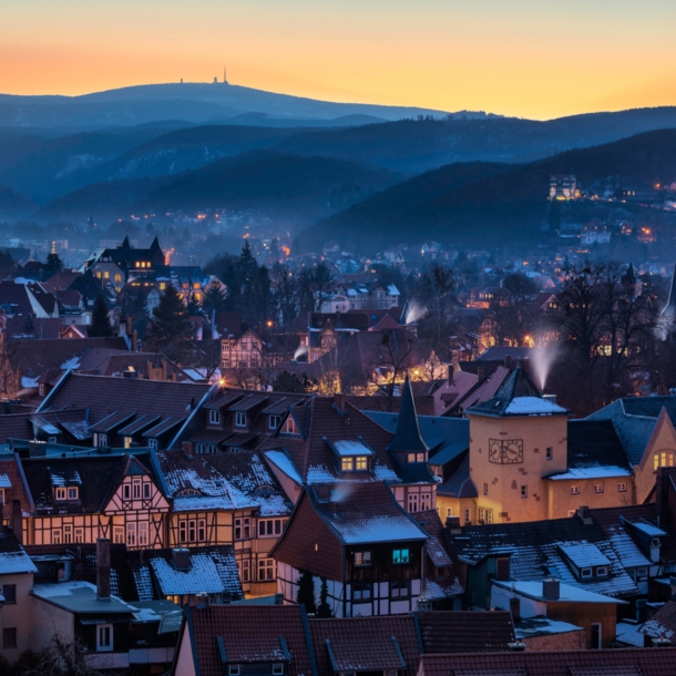 Blick auf eine beleuchtete Fachwerkstadt vor bewaldeten Hügeln