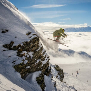 Eine Person auf Ski fliegt einen schneebedeckten Hang hinab