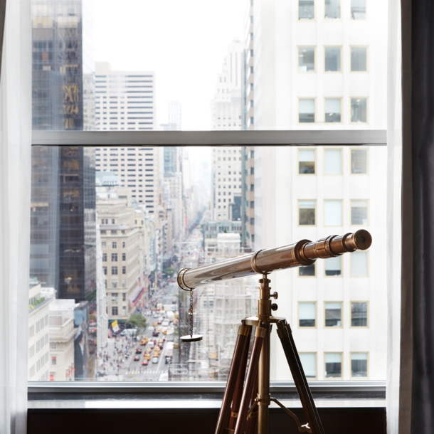 Blick durch ein Fenster auf die Fifth Avenue, am Fenster steht ein Fernrohr