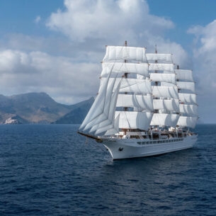 Großes Segelschiff auf dem Meer, im Hintergrund Berge