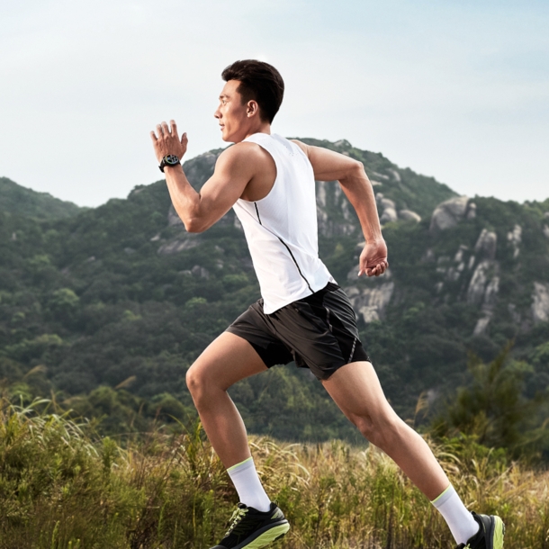 Mann joggt im Sportdress, im Hintergrund ein bewaldeter Berg