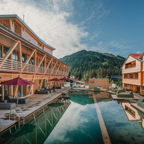 Ein Luxushotelanlage aus Holz mit Außenpool und Blick auf die Berge