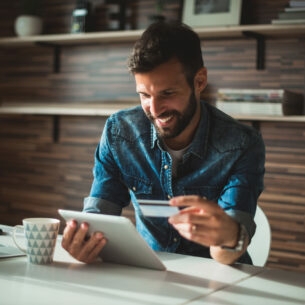 Ein lächelnder Mann am Schreibtisch beim Online-Banking