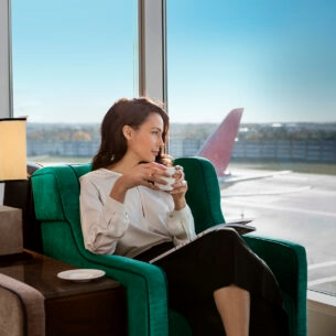 Eine Frau genießt in einer Airport-Lounge eine Tasse Kaffee