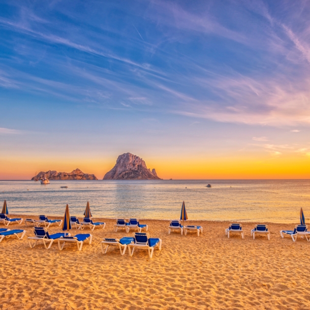 Ein Sandstrand mit Liegen bei Sonnenuntergang