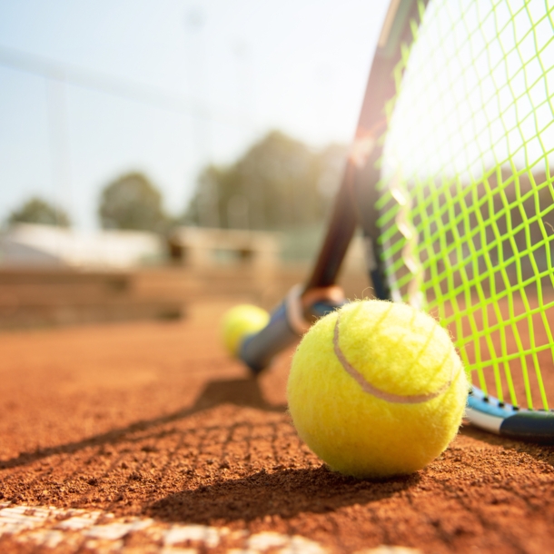 Tennisball und Schläger auf einem Tennisplatz bei schönem Wetter