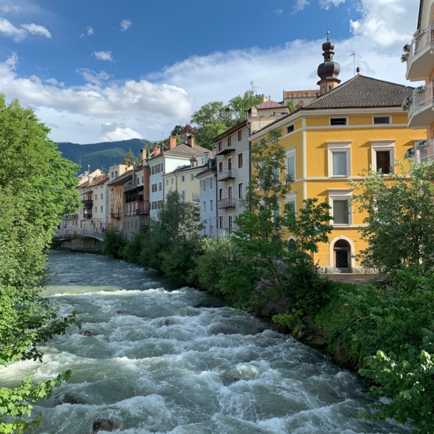 Ein Fluss verläuft inmitten von Gebäuden in Bruneck gegen den Himmel