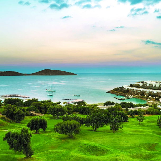 Panorama eines hügeligen Golfplatzes mit Hotelanlage am Meer