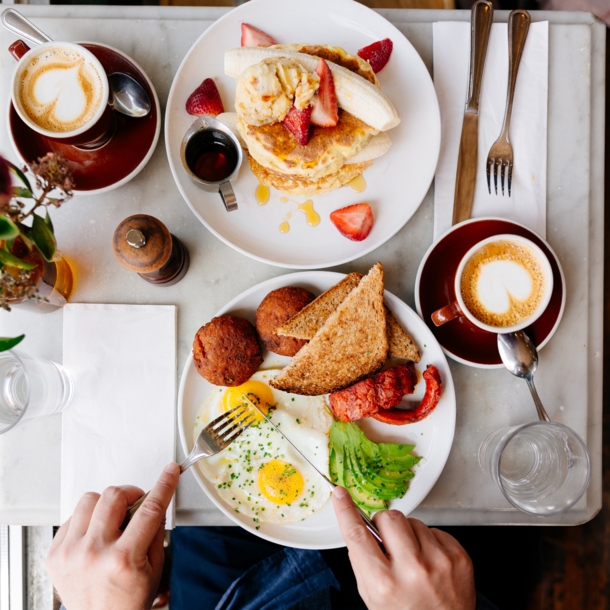 Aufsicht eines gedeckten Tisches mit Kaffeetassen und Speisen zum Brunchen