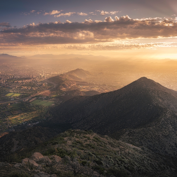 Luftbild von Santiago de Chile mit Sonne hinter Wolken