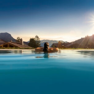 Rückansicht einer Person in einem Pool, im Hintergrund Berge