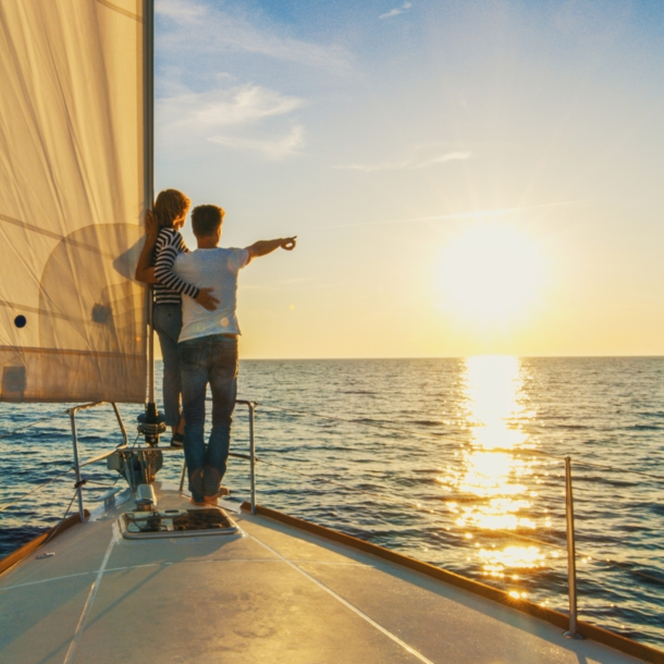 Ein Paar schaut sich auf einem Segelboot den Sonnenuntergang an 