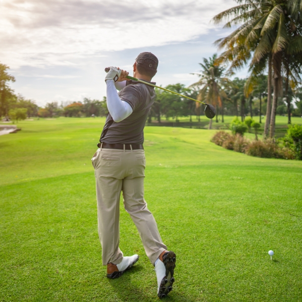 Ein Mann steht auf einem Golfplatz und hat gerade einen Ball abgeschlagen.