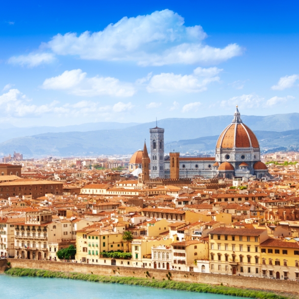 Blick auf eine mediterrane Stadt am Fluss mit historischen Gebäuden und einer Kathedrale