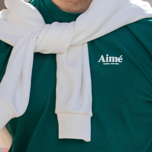 Oberkörper eines sportlichen Mannes in einem grünen T-Shirt mit dem Schriftzug der Marke Aimé