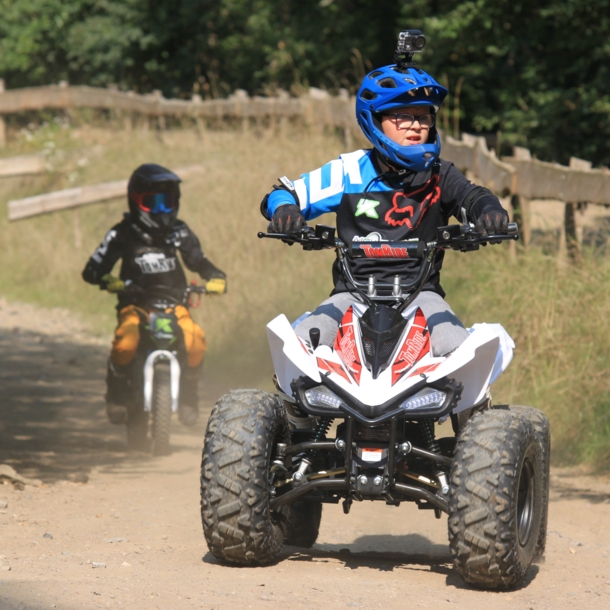 Ein Junge fährt auf einem E-Quad über unbefestigtes Gelände.