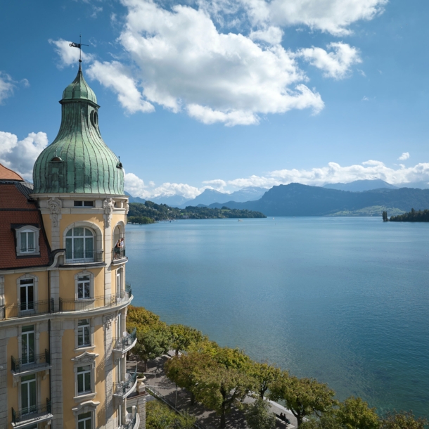 Hotel am See, im Hintergrund Berge und Wolken