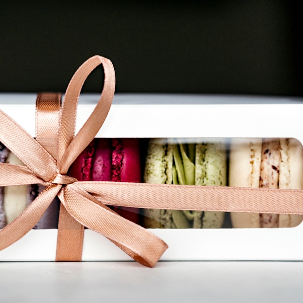 Eine Packung Macarons, dekoriert mit einem beigen Geschenkband