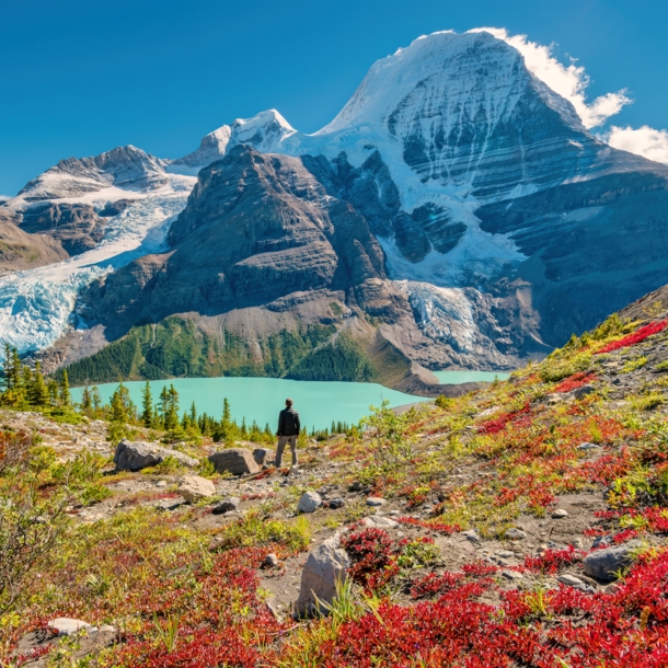 Ein Wanderer steht an einem See im Gebirge eines Nationalparks in Kanada