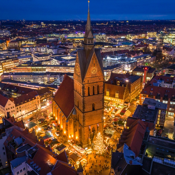 Blick von oben auf eine beleuchtete Stadt bei Nacht mit einer Kirche im Fokus