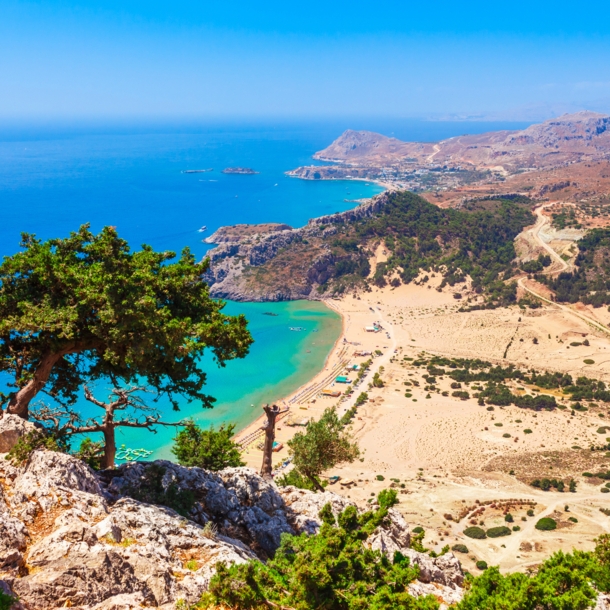 Blick von einem Berg auf einen Strand und hellblaues Wasser