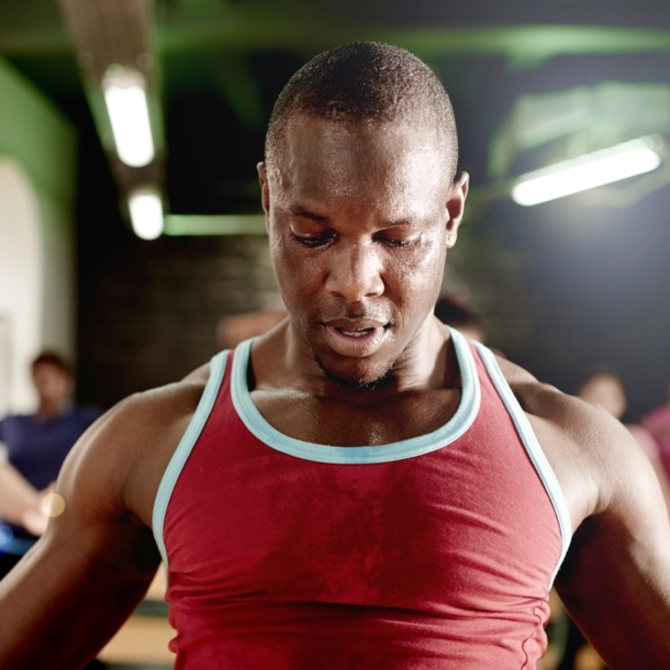 Eine schwitzende Person treibt zusammen mit anderen Personen im Studio intensiv Sport