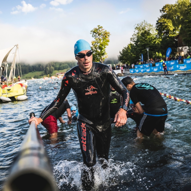 Eine Person im Neoprenanzug steigt aus einer Wasserquelle heraus