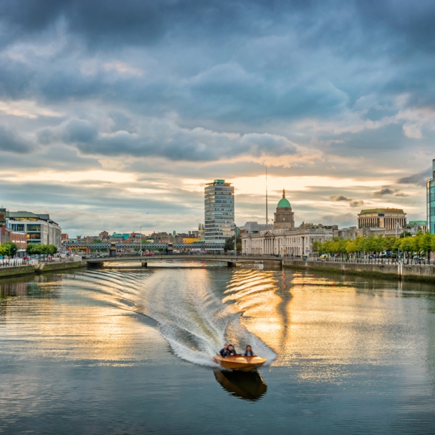 Ein Motorboot fährt auf dem Liffey River in Dublin bei Sonnenuntergang