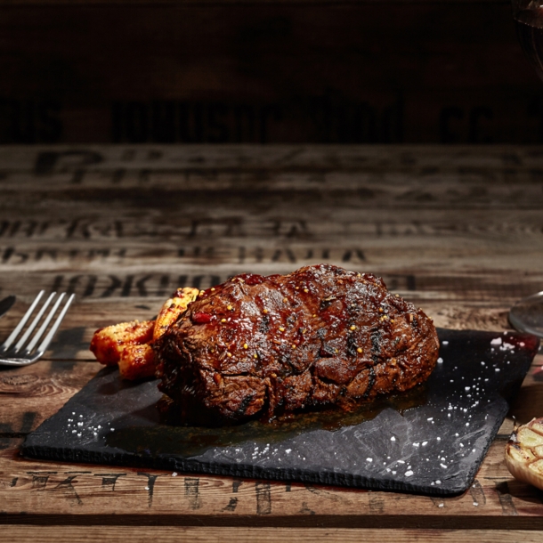 Ein gebratenes Steak liegt auf einer Granitplatte auf einem Holztisch