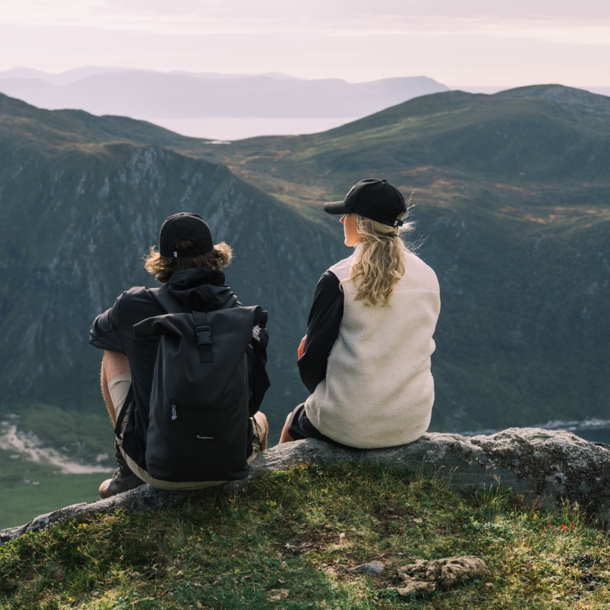 Eine Frau und ein Mann sitzen auf einem Bergvorsprung und schauen in die Ferne