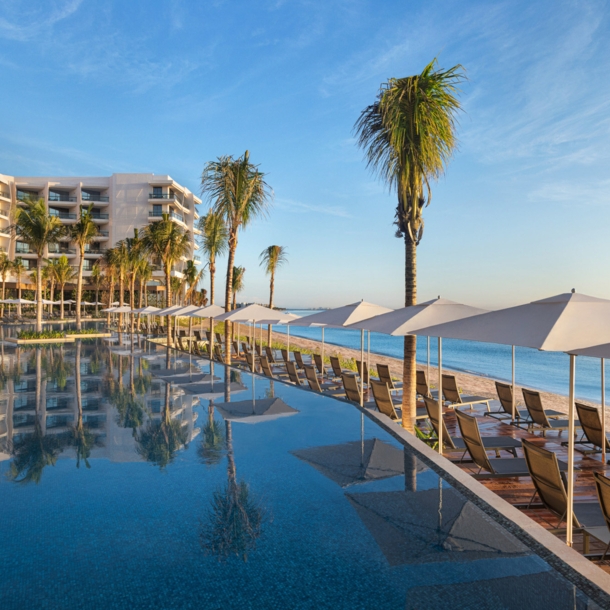 Eine Hilton Hotelanlage mit Pool an einem Sandstrand