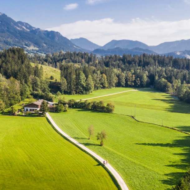 Blick auf eine Landschaft mit Bergen, Wiesen und einem Bach