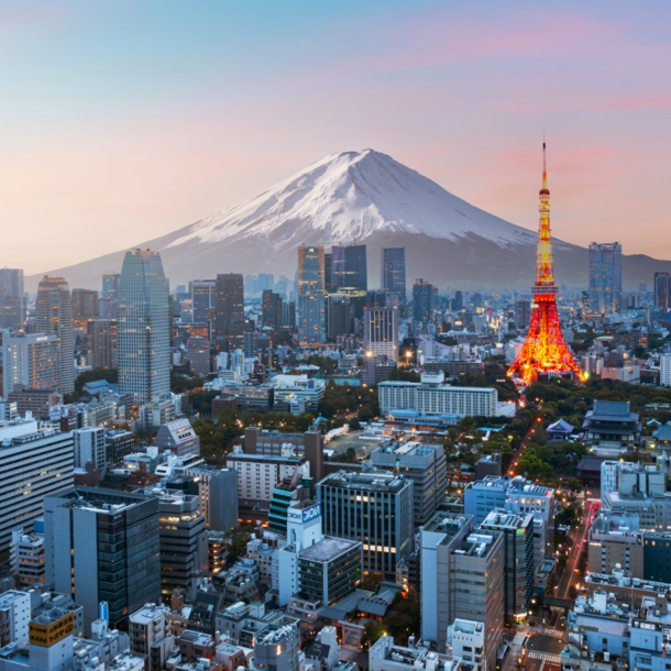 Skyline von Tokio mit beleuchtetem Fernsehturm vor schneebedecktem Fuji in der Abenddämmerung