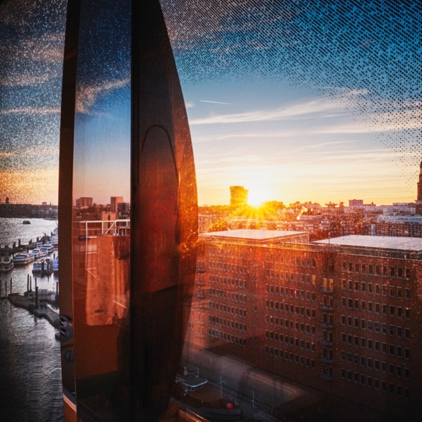 Stadtpanorama von Hamburg am Hafen aus einem geschwungenen Fenster bei Sonnenuntergang.